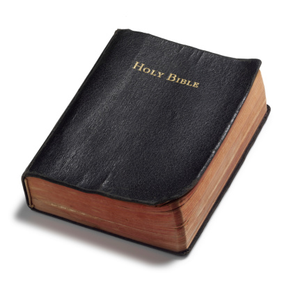 Well read Holy Bible shot at an angle on white surface with soft shadow
