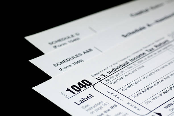 Tax Forms on Black Three US income tax forms on a black background.  Narrow dof with focus on the number '1040'.Other tax-related images: 1040 tax form photos stock pictures, royalty-free photos & images