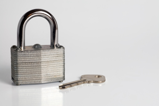 padlock on light surface with key resting in front of it