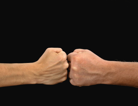 Two opposing male fists on a black background