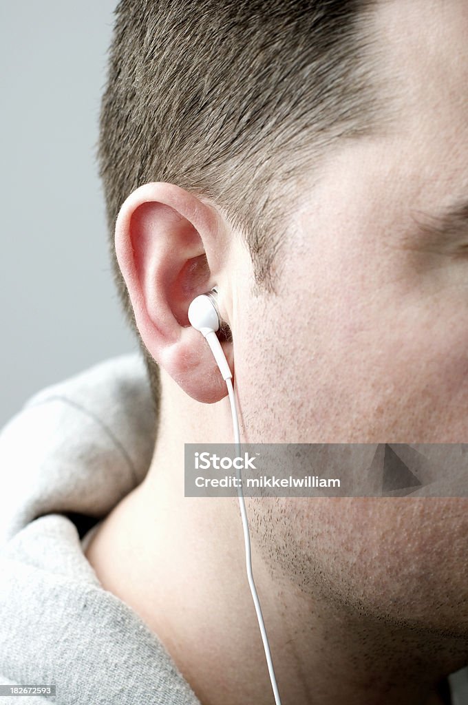 Close up of in ear with small headphone Listening to music trough a white earbud headphone. Adult Stock Photo