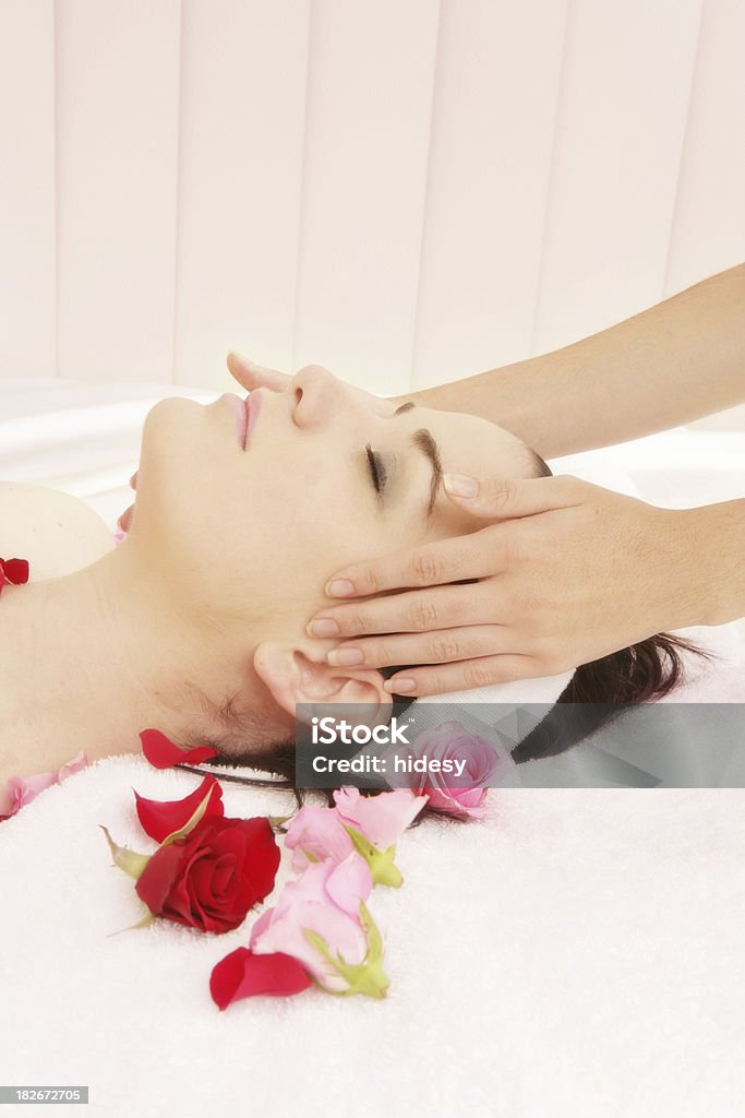 Pure Pleasure Young woman receiving a facial with pale pink background and roses in foreground Facial Mask - Beauty Product Stock Photo