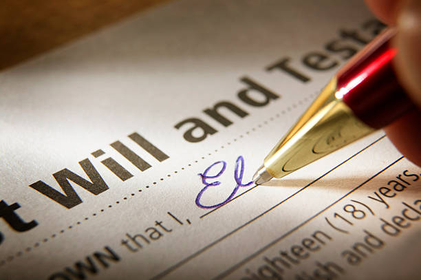 Man Signing Last Will & Testament Signing Last Will and Testament. A shallow depth of field focuses putting the pen to paper finalizing the process of securing one's legacy. A red and gold ballpoint pen writes in blue ink and the writer begins to commit their name to paper in elegant blue cursive.  A pleasant reflection bounces off the gold pen.  last stock pictures, royalty-free photos & images