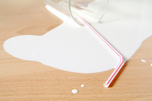 Detail image of a spilled glass of milk on a hardwood floor. No need to cry.