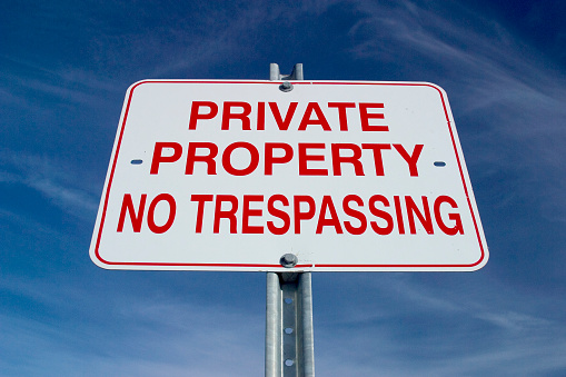 Sign depicting Private Property shot against graduated blue sky with light clouds.