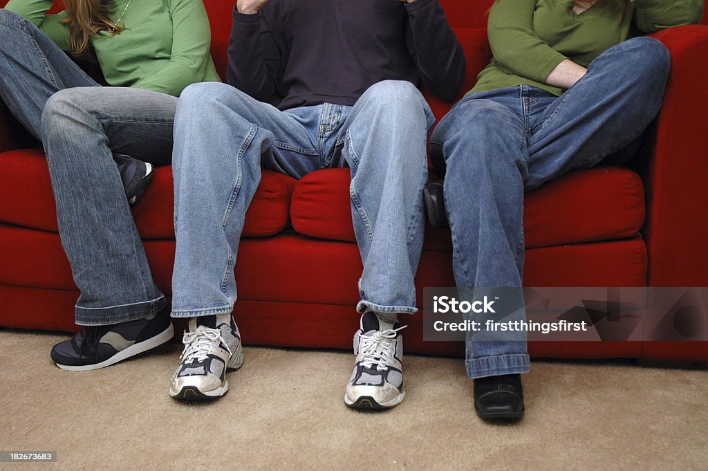 Legs1 3 people on a red couch with heads cropped off. Animal Body Stock Photo