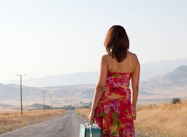 istock Young woman hitchhiking on open road 182673799