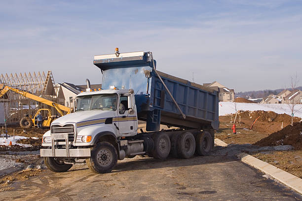 Working Dump Truck on Contstruction Site Logos and trademarks have been removed. Men working are unrecognizable. Bright sunny winter day. dump truck photos stock pictures, royalty-free photos & images