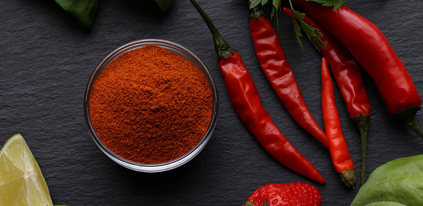 Chili pepper and pepper powder on a black background.