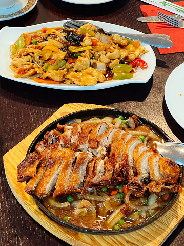 Sweet and sour chicken and Sichuan duck stand on plates on a table in a restaurant. High quality photo
