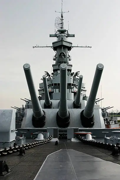 Shot of the battleship USS Alabama, docked in Mobile, AL, taken from just in front of the main guns. Focus is on the tip of the middle gun barrel.