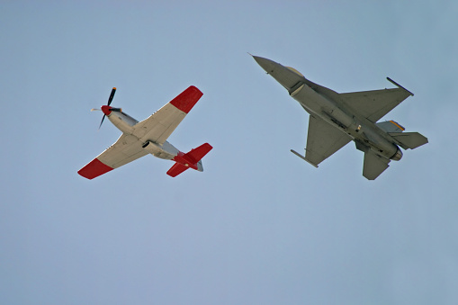 Vintage propeller fighter plane and an new jet fighter fly side by side.