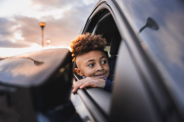 Young African American boy peering out of the car window, during the sunset. stock photo