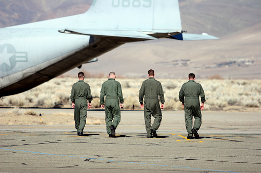 Four enlisted Marines walking confidently back to their C-130.  