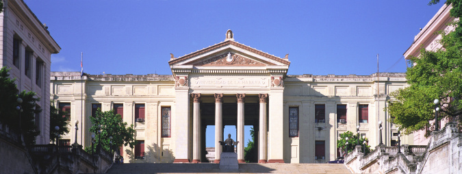 A low angle shot of a Palladian Basilica with arches, columns and statues under a blue sky in Italy