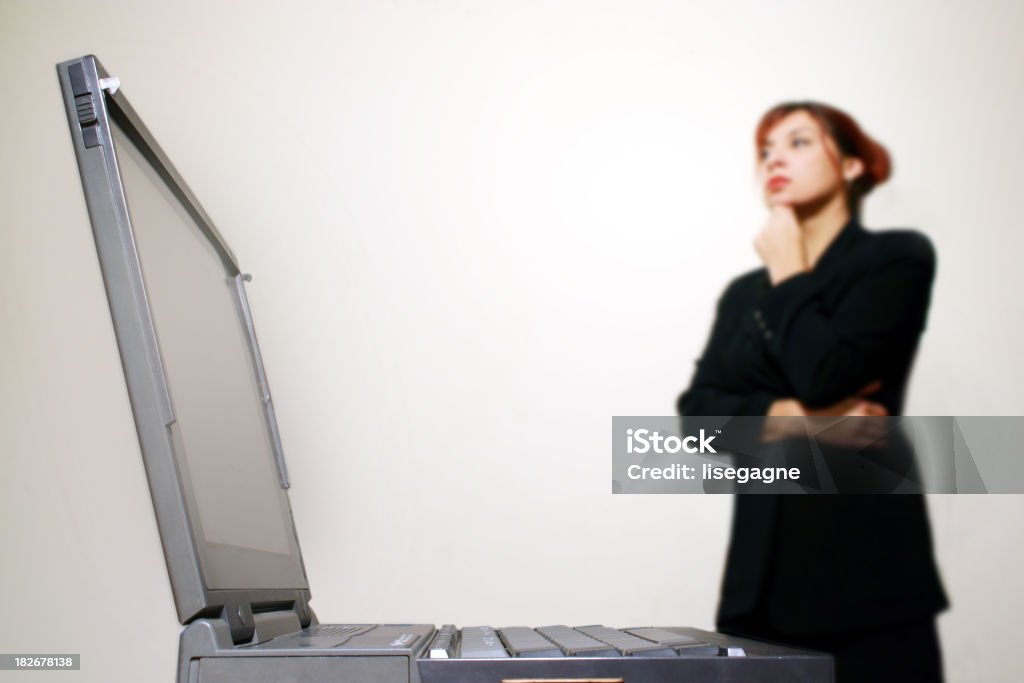 Задумчивый женщина, стоя рядом с ноутбук - Стоковые фото Белый фон роялти-фри