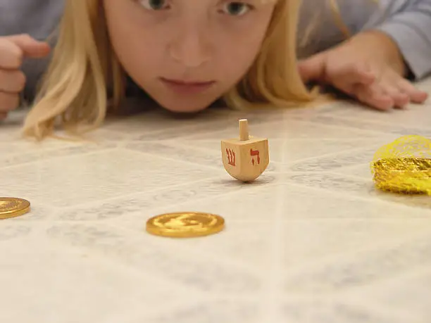 Young girl playing the dreidel game. Notes: Dreidel is sharp girl fades in depth of field.