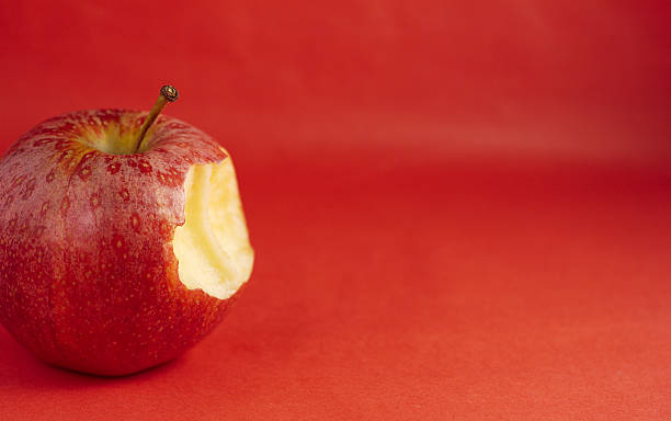 Requests aple Bitten red apple on red background. apple bite stock pictures, royalty-free photos & images