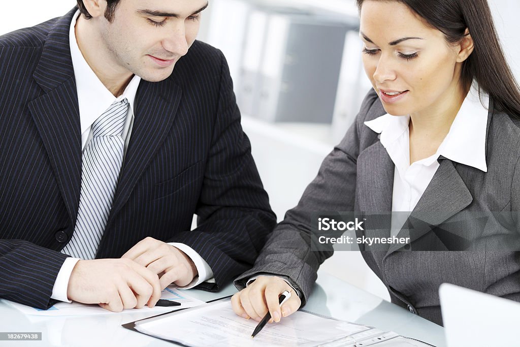 Two contemporary business persons working with documents. Two contemporary business persons working with documents in the office. Adult Stock Photo