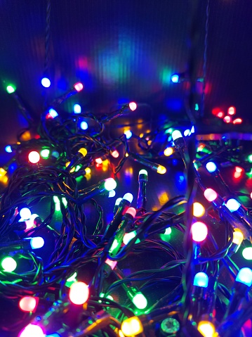 christmas tree decorations and old lamp garland for illumination on defocused blue background