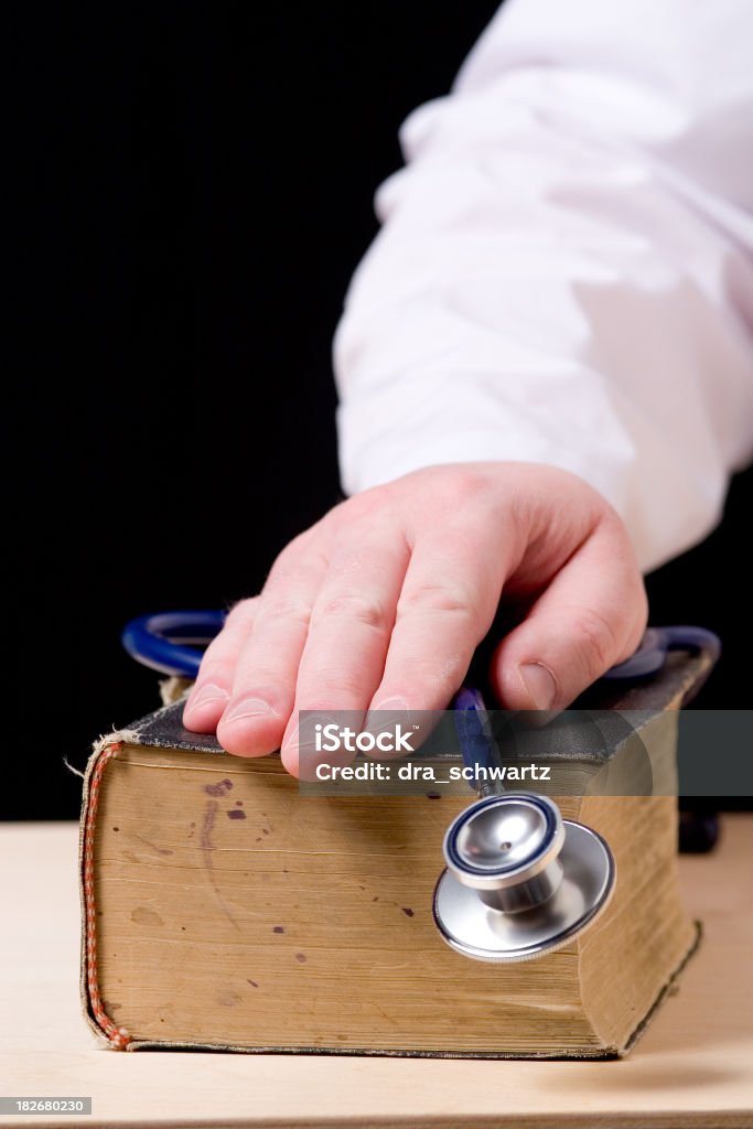 Mano con Stetoscopio sopra vecchio libro - Foto stock royalty-free di Ippocrate