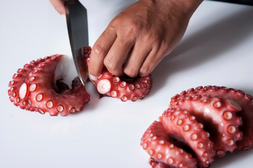 A Japanese Sushi Chef Cutting Raw Octopus.