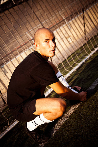fußballspieler binden seine schuh am ziel - soccer field soccer single line field stock-fotos und bilder