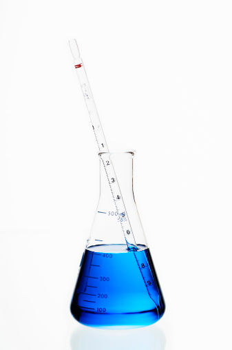 Erlenmeyer filled with blue liquid on highkey background