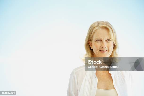 Mujer De Pie Contra El Cielo Azul Foto de stock y más banco de imágenes de 50-54 años - 50-54 años, 50-59 años, Adulto