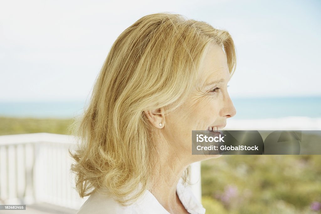 Vista lateral de una mujer madura mirando al aire libre - Foto de stock de Aire libre libre de derechos