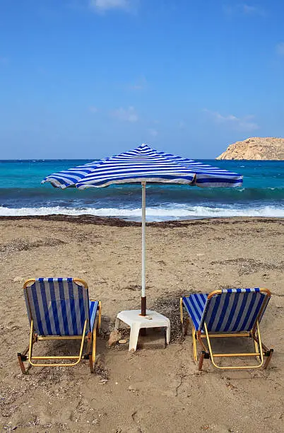 Two deck chairs and umbrella on the beach.