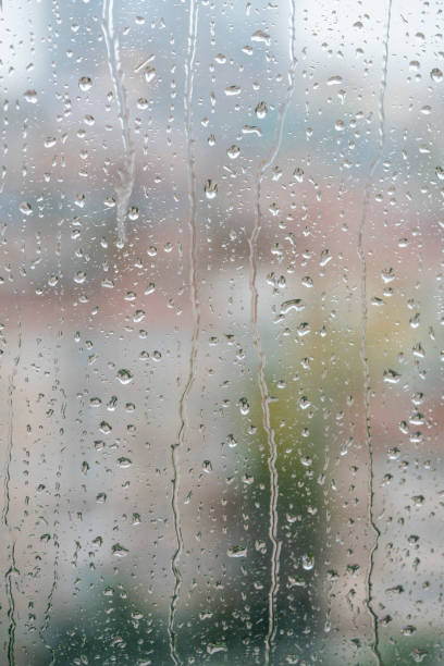 istock raindrops on windowpane over blurred city view. 1826833388