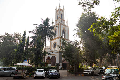 This image showcases St. Thomas Cathedral in Mumbai, a historic Anglican church and one of the city's oldest colonial buildings. The cathedral, named in honour of Saint Thomas the Apostle, is an embodiment of 18th-century British colonial architecture, with its simple yet elegant structure. The photograph captures the church's façade, featuring classic Gothic arches and stained glass windows that add a touch of grace to its sturdy construction. Nestled amidst the bustling streets of Mumbai, St. Thomas Cathedral stands as a peaceful sanctuary, offering a quiet retreat from the city's frenetic pace. The image aims to highlight the cathedral's architectural beauty and historical significance, portraying it as a symbol of Mumbai's colonial past and a landmark of spiritual solace in the heart of a modern metropolis.
