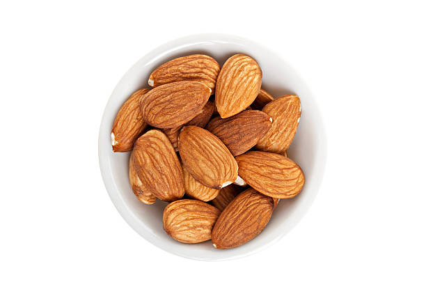 A white bowl of almonds on a white background.