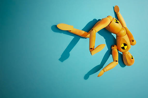 Crash Test Dummy A crash test dummy sprawled in an akward position. Shot on a blue background and a sharop spotlight. falling behind stock pictures, royalty-free photos & images