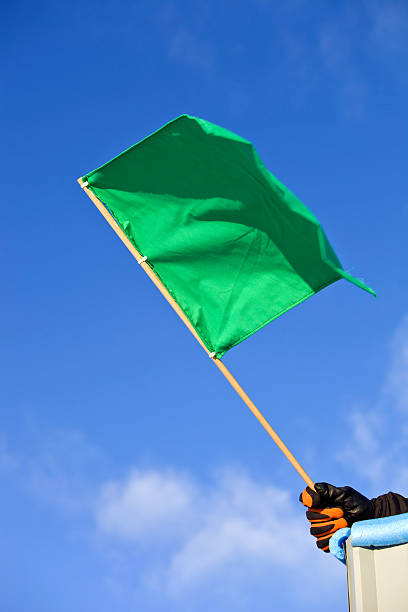 verde bandeira automático de corrida contra o céu limpo e azul - checkered flag flag auto racing starting line - fotografias e filmes do acervo