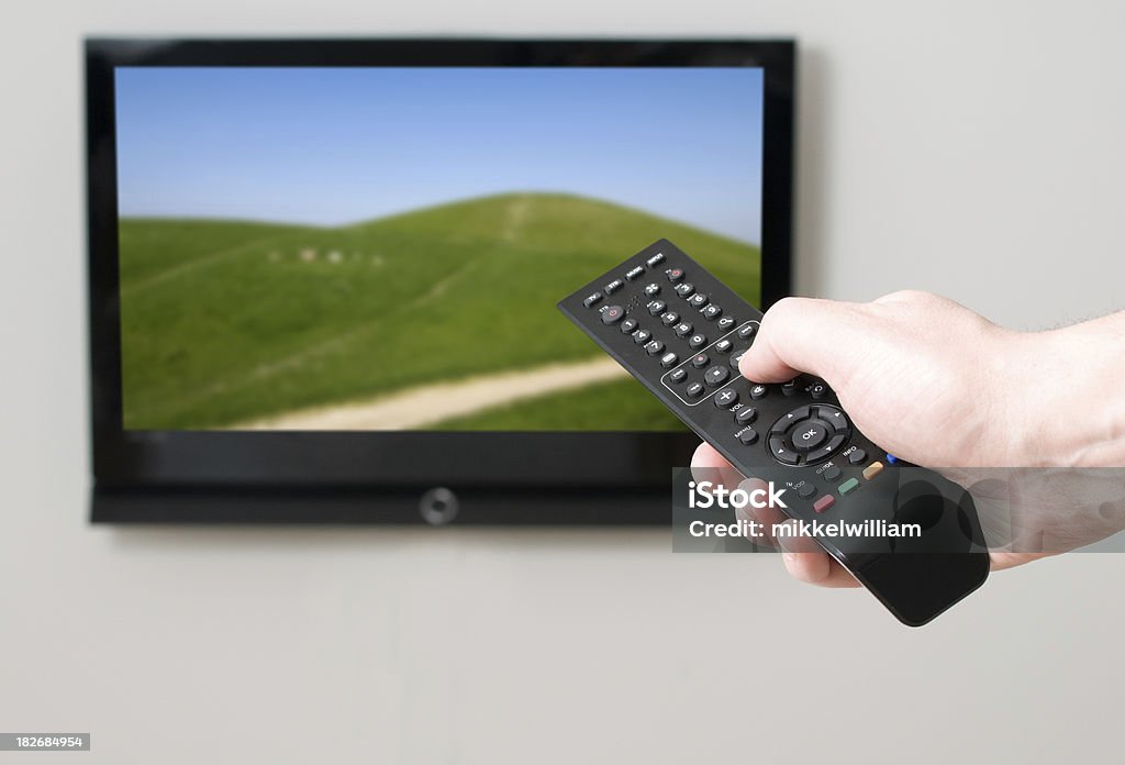 Controllo remoto che indica una tv a schermo piatto con immagini della hills - Foto stock royalty-free di Aggiustare