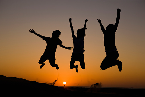 Silhouette of a happy woman jumping. Unrecognizable young female.