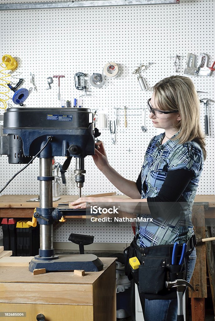 Woman drilling at a drill press A woman drilling lumber in a wood shop. Adult Stock Photo