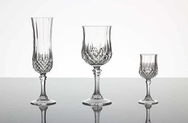 Lead cut glass crystal stemware "A champagne flute, wine glass and liqueur glass made out of cut glass (crystal glass or lead glass), on plain gray shiny surface with gray background" lead cut glass crystal stemware stock pictures, royalty-free photos & images