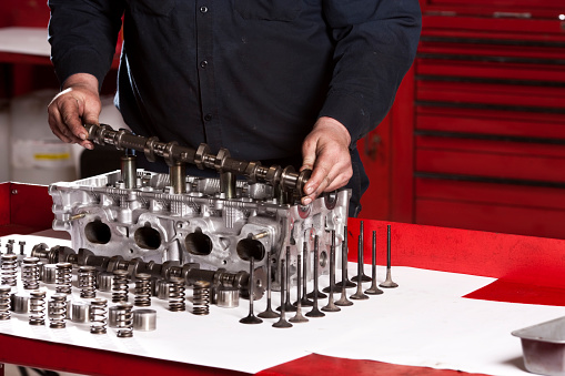Close up of a mechanic setting a camshaft in an engine block that he is rebuilding.