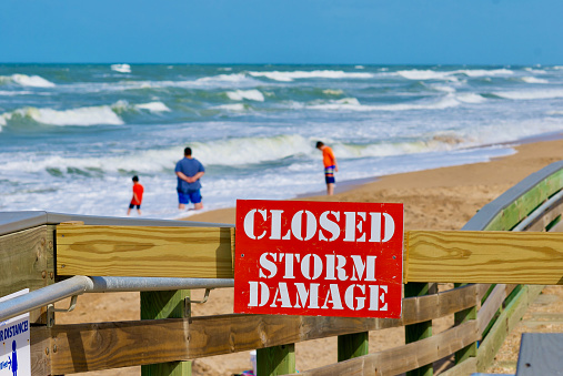New Smyrna Beach, Florida, USA - June 2, 2020: A sign warns visitors that a wooden beach access ramp is “Closed”as the result of storm damage from a hurricane at Mary McLeod Bethune Beach Park.