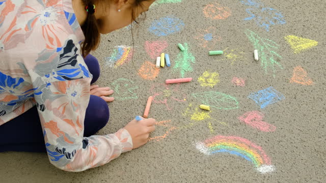 a child draws with chalk on the asphalt. Selective focus. kid.