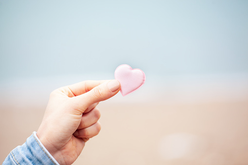 Woman hand holding pink heart. Young hand holding or giving a pink heart, concept of family and donation or adoption, health care and medicine concept. Valentines Day concept. Breast Cancer Awareness concept.