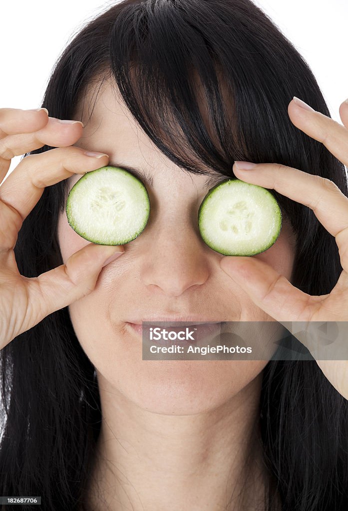 Jeune femme tenant deux tranches de concombre sur ses yeux - Photo de Adulte libre de droits