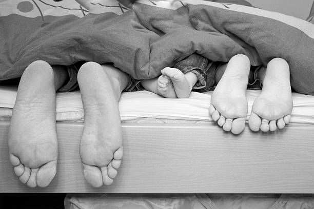 Shot of a pair of woman's feet poking out from under the sheets of a bed