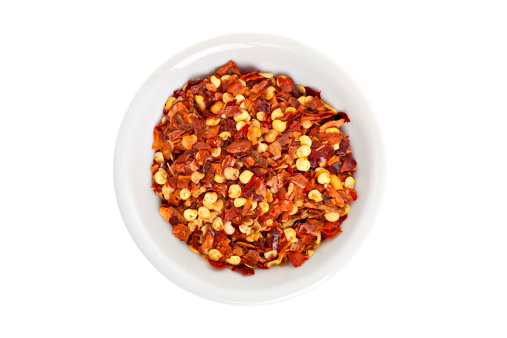 Red hot chili pepper seeds and flakes on a white background.
