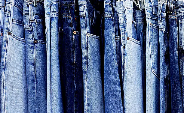 "A rack of a variety of blue denim jeans in various shades of blue. Texture, patterns and variety."