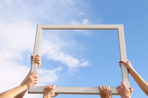 Three women holding a frame and showing clouds. Add your message.