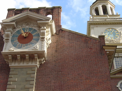 Two clocks at Independence Hall in Phila, PA, one on side wall of brick building and one on bell tower at almost 1:00PM